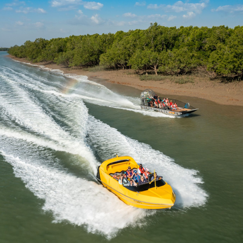 A yellow speedboat filled with passengers races across a river